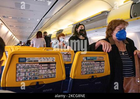 Passagiere tragen während des Fluges eine Gesichtsbedeckung in der Kabine. Fliegen während der Coronavirus-Pandemie Covid-19 in einer Boeing 737-800 der Billigfluggesellschaft Ryanair mit Ziel Chania auf Kreta, einem beliebten Urlaubsziel. Im Flugzeug ist es obligatorisch, Gesichtsmasken für die Passagiere und die Flugbesatzung, die Flugbegleiterin usw. zu tragen, während die Menschen als Sicherheitsmaßnahme einen negativen COVID-Test benötigen, um an Bord zu gehen, während die Luft- und Tourismusindustrie sich bemüht, zur Normalität zurückzukehren. Griechenland versucht, seinen Tourismus anzukurbeln und Privilegien für Impfungen gegen Cov zu geben Stockfoto