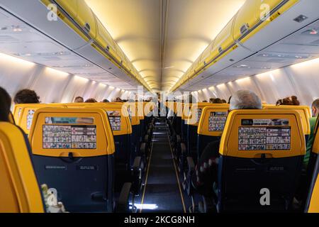 Fliegen während der Coronavirus-Pandemie Covid-19 in einer Boeing 737-800 der Billigfluggesellschaft Ryanair mit Ziel Chania auf Kreta, einem beliebten Urlaubsziel. Im Flugzeug ist es obligatorisch, Gesichtsmasken für die Passagiere und die Flugbesatzung, die Flugbegleiterin usw. zu tragen, während die Menschen als Sicherheitsmaßnahme einen negativen COVID-Test benötigen, um an Bord zu gehen, während die Luft- und Tourismusindustrie sich bemüht, zur Normalität zurückzukehren. Griechenland versucht, seinen Tourismus anzukurbeln und Privilegien für Impfungen gegen die Pandemie Covid-19, internationale Touristen und Einheimische, als CO, zu gewähren Stockfoto