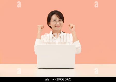 Lehrer oder Büroangestellte heben beide Hände vor dem Laptop und geben Hoffnung, Mut und Selbstvertrauen Stockfoto