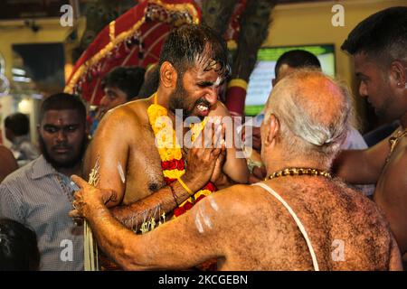 Tamilischer Hindu-Anhänger erhält Segen von einem Hindu-Priester, nachdem er das para-kavadi-Ritual (ein Ritual, bei dem er von Haken in seinen Rücken und seine Beine getrieben wird und beim Umkreisen des Tempels als Bußakt auf und ab prallte) während des Vinayagar Ther Thiruvizha Festivals in Ontario durchgeführt hat, Kanada am 23. Juli 2006. Die Gläubigen bereiten sich auf die Feier vor, indem sie sich 11 bis 25 Tage vor dem Fest durch Gebet, Zölibat und Fasten reinigen. Während dieses religiösen Festivals zeigen mehrere Anhänger ihre Hingabe, indem sie Opfer darbringen und ihre Körper mit Metallhaken und durchbohren Stockfoto