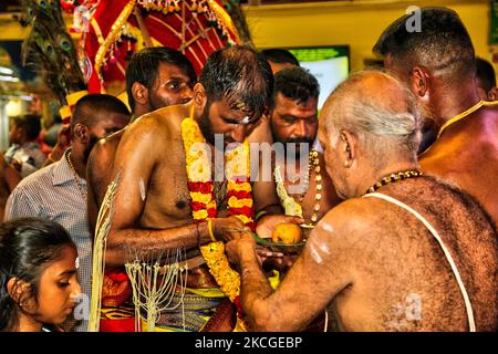 Tamilischer Hindu-Anhänger erhält Segen von einem Hindu-Priester, nachdem er das para-kavadi-Ritual (ein Ritual, bei dem er von Haken in seinen Rücken und seine Beine getrieben wird und beim Umkreisen des Tempels als Bußakt auf und ab prallte) während des Vinayagar Ther Thiruvizha Festivals in Ontario durchgeführt hat, Kanada am 23. Juli 2006. Die Gläubigen bereiten sich auf die Feier vor, indem sie sich 11 bis 25 Tage vor dem Fest durch Gebet, Zölibat und Fasten reinigen. Während dieses religiösen Festivals zeigen mehrere Anhänger ihre Hingabe, indem sie Opfer darbringen und ihre Körper mit Metallhaken und durchbohren Stockfoto