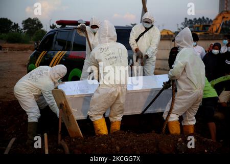 In Schutzkleidung (Hazmat) mit der Aufschrift „Stop, Don't Add More“ (Stop Jangan Nambah Lagi) werden die Leichname des COVID-19 am 26,2021 auf dem öffentlichen Friedhof von Rorotan, North Jakarta, begraben. Die Bestattungsbeamten haben ihre Aufgaben ohne Unterbrechung erfüllt, da es eine Zunahme des Covid-19-Virus-Falles gab, sie begruben die Leichen von etwa 80 bis 100 weiteren Covid-19-Särgen an einem Tag von morgens bis abends. (Foto von Dasril Roszandi/NurPhoto) Stockfoto