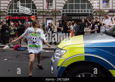 LONDON, GROSSBRITANNIEN – 27. JUNI 2021: Eine Frau tanzt vor einem Polizeiwagen, während Tausende von Menschen an einem von Save Our Scene organisierten protestmarsch der „Freedom to Dance“ durch das Zentrum Londons teilnehmen und fordern, dass die britische Regierung am Juni die Beschränkungen des Coronavirus, die dem Musik- und Gastgewerbe auferlegt wurden, ohne weitere Verzögerung aufhebt 27, 2021 in London, England. Die britische Nachtwirtschaft ist von den Beschränkungen von Covid-19 schwer betroffen, wobei die meisten Veranstaltungsorte seit Beginn der Pandemie geschlossen waren. (Foto von Wiktor Szymanowicz/NurPhoto) Stockfoto