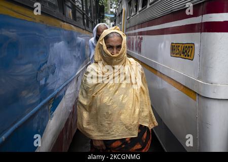 Eine alte Frau, die keine Sicherheitsmaske trug, bedeckte ihr Gesicht mit einem Tuch und überquerte am 1. Juli 2021 die Fahrspur einer Busstation in Kalkutta, Indien. West Bengalen Govt hat bestimmte Beschränkungen für die Sperre in Kraft gesetzt, die vom 1.. juli bis zum 15.. juli wirksam ist. Busse, Autos und toto-Dienste wurden mit einer Kapazität von 50 % wieder aufgenommen. Salon, Salon und Fitnessstudio können mit 50% Kunden eröffnet werden. Der lokale Zug und die U-Bahn werden laut dem indischen Medienbericht nicht in Betrieb sein. Obwohl die Busverbindungen nicht regelmäßig waren, da die Busverbände protestierten, den Bustarif zu steigen, und appellierten für eine Zwangsimpfung für alle Stockfoto