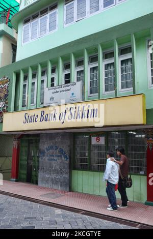 Zwei Männer gehen entlang der Mahatma Gandhi Road an der State Bank of Sikkim in Gangtok, Sikkim, Indien, vorbei. Die State Bank of Sikkim wirbt für die Vorteile, mit ihnen Geld zu sparen, indem sie „Spesen und Schutz unter einem Dach“ anbietet. Banken sind eine relativ neue Institution in Sikkim und müssen das Vertrauen eines Volkes gewinnen, das traditionell Geld zu Hause hält. (Foto von Creative Touch Imaging Ltd./NurPhoto) Stockfoto