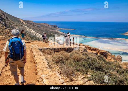 Touristen genießen den Blick auf Balos, während sie auf dem Weg zum Strand gehen. Panoramablick auf den Balos Beach, die unglaubliche Lagune mit dem türkisfarbenen exotischen und tropischen Wasser des Mittelmeers, befindet sich in der Region Chania auf der Insel Kreta. Balos ist einer der meistbesuchten Strände Kretas und beliebt bei Besuchern auf der ganzen Welt. Kristallklares Wasser, die Lagune, felsige steile Berge, eine Strandbar mit Sonnenschirmen und Schatten mit Getränken und eine Pirateninsel befinden sich in derselben Region, die mit einem 20-minütigen Trek oder Boot erreichbar ist. Griechenland versucht, seine T-Leistung zu steigern Stockfoto