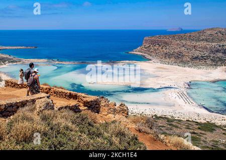 Touristen genießen den Blick auf Balos, während sie auf dem Weg zum Strand gehen. Panoramablick auf den Balos Beach, die unglaubliche Lagune mit dem türkisfarbenen exotischen und tropischen Wasser des Mittelmeers, befindet sich in der Region Chania auf der Insel Kreta. Balos ist einer der meistbesuchten Strände Kretas und beliebt bei Besuchern auf der ganzen Welt. Kristallklares Wasser, die Lagune, felsige steile Berge, eine Strandbar mit Sonnenschirmen und Schatten mit Getränken und eine Pirateninsel befinden sich in derselben Region, die mit einem 20-minütigen Trek oder Boot erreichbar ist. Griechenland versucht, seine T-Leistung zu steigern Stockfoto