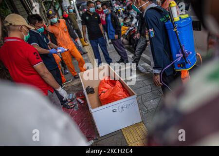 Beamte bereiten sich darauf vor, den Leichnam eines 66-Mann in einem Sarg zu transportieren, nachdem er am 9. Juli 2021 in Jakarta tot auf einer Bank im Stadtzentrum gefunden wurde, die des COVID-19-Coronavirus verdächtigt wurde. Indonesien verhängte aufgrund der neuen Zunahme von COVID-19 auf Java und Bali Notbeschränkungen. Seit Beginn der Pandemie hat das Land mehr als 2.400.000 Fälle von Coronavirus-Erkrankungen (COVID-19) mit über 64.000 Todesfällen verzeichnet. (Foto von Afriadi Hikmal/NurPhoto) Stockfoto