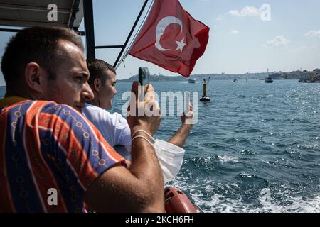 In Istanbul, Türkei, wurden die Maßnahmen zur sozialen Distanzierung des Coronavirus am 1. Juli 2021 gelockert, nachdem die neuen täglichen Fälle von Covid-19 im Rahmen einer schnellen Impfbemühung gefallen waren. Die städtischen Gebiete sind wieder voll von türkischen Menschen mit Gesichtsmasken und Touristen, die in den Straßen der Stadt spazieren gehen und häufig touristische Attraktionen besuchen, während sie das heiße Sommerwetter genießen. Oben machen Passagiere am 11. Juli 2021 mit ihren Smartphones Fotos, während sie mit einer Fähre auf der Straße des Bosporus fahren. (Foto von Diego Cupolo/NurPhoto) Stockfoto