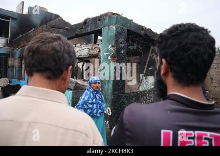 Kashmiri-Menschen bewerten das beschädigte Wohnhaus, in dem am 14. Juli 2021 bei einer Militäroperation im Gebiet Newa im Distrikt Pulwama im indischen Kaschmir drei Militante getötet wurden. (Foto von Muzamil Mattoo/NurPhoto) Stockfoto