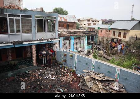 Kashmiri-Menschen bewerten das beschädigte Wohnhaus, in dem am 14. Juli 2021 bei einer Militäroperation im Gebiet Newa im Distrikt Pulwama im indischen Kaschmir drei Militante getötet wurden. (Foto von Muzamil Mattoo/NurPhoto) Stockfoto