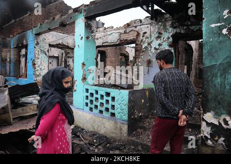 Kashmiri-Menschen bewerten das beschädigte Wohnhaus, in dem am 14. Juli 2021 bei einer Militäroperation im Gebiet Newa im Distrikt Pulwama im indischen Kaschmir drei Militante getötet wurden. (Foto von Muzamil Mattoo/NurPhoto) Stockfoto