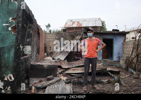 Kashmiri-Menschen bewerten das beschädigte Wohnhaus, in dem am 14. Juli 2021 bei einer Militäroperation im Gebiet Newa im Distrikt Pulwama im indischen Kaschmir drei Militante getötet wurden. (Foto von Muzamil Mattoo/NurPhoto) Stockfoto