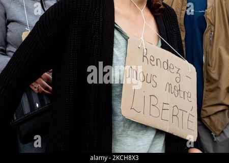 Ein Demonstrator hat ein Schild mit der Aufschrift „Give US back our Freedom“, das am 14. Juli 2021 um ihren Hals hängt, 2 Tage nach der letzten Rede des Präsidenten der Französischen Republik Emmanuel Macron zur Einführung einer obligatorischen Impfung von Pflegekräften und der Verallgemeinerung des Health Pass an öffentlichen Orten von mehr als 50 Menschen, um mit einem Wiederaufleben von Covid in Frankreich nach dem Aufkommen der fertig zu werden Delta Variante, versammelten sich mehrere hundert Menschen in den Straßen von Paris, um ihre Opposition zu demonstrieren. Diese Demonstration wurde schnell von der Bereitschaftspolizei unterdrückt, was zu Zusammenstößen mit dem Demonstrato führte Stockfoto