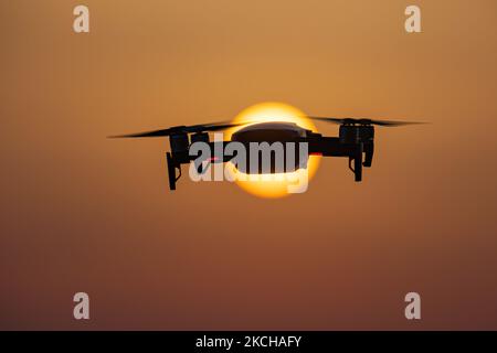 Eine Quadcopter-Drohne schwebt während eines Fluges vor der Sonne. Die fliegende Drohne wird als dunkle Silhouette gegen den spektakulären, farbenfrohen Sonnenuntergangshimmel und die Sonne gesehen, während die UAV in der Lage ist, Luftaufnahmen und Fotos über eine Fernbedienung aufzunehmen. Die spezifische Drohne ist eine DJI Mavic Air. Das unbemannte Luftfahrzeug ist bei Touristen beliebt, da die Technologie für jedermann in niedrigen Kosten zugänglich ist, aber auch viele professionelle Anwendungen hat Sani Beach Area, Chalkidiki, Griechenland am 15. Juli 2021 (Foto von Nicolas Economou/NurPhoto) Stockfoto