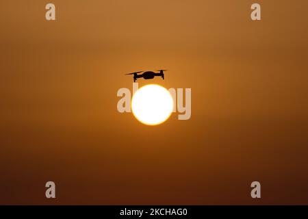 Eine Quadcopter-Drohne schwebt während eines Fluges vor der Sonne. Die fliegende Drohne wird als dunkle Silhouette gegen den spektakulären, farbenfrohen Sonnenuntergangshimmel und die Sonne gesehen, während die UAV in der Lage ist, Luftaufnahmen und Fotos über eine Fernbedienung aufzunehmen. Die spezifische Drohne ist eine DJI Mavic Air. Das unbemannte Luftfahrzeug ist bei Touristen beliebt, da die Technologie für jedermann in niedrigen Kosten zugänglich ist, aber auch viele professionelle Anwendungen hat Sani Beach Area, Chalkidiki, Griechenland am 15. Juli 2021 (Foto von Nicolas Economou/NurPhoto) Stockfoto