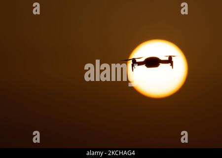 Eine Quadcopter-Drohne schwebt während eines Fluges vor der Sonne. Die fliegende Drohne wird als dunkle Silhouette gegen den spektakulären, farbenfrohen Sonnenuntergangshimmel und die Sonne gesehen, während die UAV in der Lage ist, Luftaufnahmen und Fotos über eine Fernbedienung aufzunehmen. Die spezifische Drohne ist eine DJI Mavic Air. Das unbemannte Luftfahrzeug ist bei Touristen beliebt, da die Technologie für jedermann in niedrigen Kosten zugänglich ist, aber auch viele professionelle Anwendungen hat Sani Beach Area, Chalkidiki, Griechenland am 15. Juli 2021 (Foto von Nicolas Economou/NurPhoto) Stockfoto