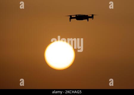 Eine Quadcopter-Drohne schwebt während eines Fluges vor der Sonne. Die fliegende Drohne wird als dunkle Silhouette gegen den spektakulären, farbenfrohen Sonnenuntergangshimmel und die Sonne gesehen, während die UAV in der Lage ist, Luftaufnahmen und Fotos über eine Fernbedienung aufzunehmen. Die spezifische Drohne ist eine DJI Mavic Air. Das unbemannte Luftfahrzeug ist bei Touristen beliebt, da die Technologie für jedermann in niedrigen Kosten zugänglich ist, aber auch viele professionelle Anwendungen hat Sani Beach Area, Chalkidiki, Griechenland am 15. Juli 2021 (Foto von Nicolas Economou/NurPhoto) Stockfoto