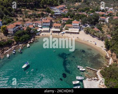 Panorama-Luftaufnahme von einer Drohne von Agios Giorgios oder Katigiorgis Village, Strand und Hafen in der Region Pelion in Griechenland mit Sonnenschein im Sommer. Katigiorgis ist ein malerisches Fischerdorf, 61km von der Stadt Volos und 3 Seemeilen von der Insel Skiathos entfernt und bietet eine einfache Möglichkeit für Touristen, die Inseln Skiathos und Sporaden oder Pilion mit der Fähre zu besuchen. Dieses Dorf ist klein, schön, friedlich und ruhig, ein abgeschiedenes Paradies im Mittelmeer, das seinen ursprünglichen Stil mit warmen Menschen behält, umgeben von üppigem Grün, Olivenhainen und niedrigen Hügeln, die nur ein paar Optionen für AC haben Stockfoto