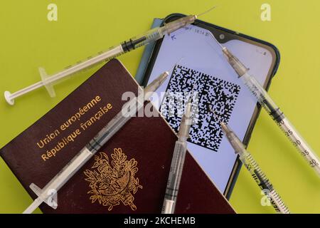 QR-Code mit EU Digital COVID Zertifikat auf dem Handy neben einem französischen Pass, medizinischen Spritzen und einer Gesichtsmaske. Am Montag, den 19. Juli 2021, in Bayeux, Calvados, Normandie, Frankreich. (Foto von Artur Widak/NurPhoto) Stockfoto