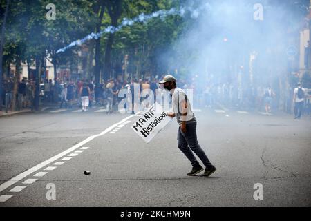 Ein Protestler, der ein Plakat mit der Aufschrift „Historischer Protest“ hält, bereitet sich darauf vor, einen Tränenbehälter zurückzuwerfen, um die Polizei aufzurührsen. Mehr als 10.000 Demonstranten gingen nach der Rede Macrons am 12.. Juli in Toulouse gegen die fast obligatorische Impfung und gegen den Gesundheitspass auf die Straße. Macron kündigte an, dass der Gesundheitspass obligatorisch sein wird, um an öffentlichen Orten wie Cafés, Theatern, Konzertsälen, Kinos, Geschäften, Öffentliche Verkehrsmittel (Zug, Bus, Straßenbahn) usw. die Verzögerung zwischen dem ersten Jab und der Bestrachtung des Gesundheitsausweise beträgt fünf Wochen. Aber das Verbot für öffentliche Räume zur Nichimpfung Stockfoto