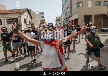Ein junger Demonstranten, der mit der Flagge Tunesiens bedeckt ist, macht die Siegeszeichen (V-Zeichen), während Demonstranten während einer Demonstration, die am 25. Juli 2021 in der tunesischen Hauptstadt Tunis stattfand, Anti-Regierungs-Slogans chanten, um zum Sturz des Regimes zu rufen, Die Auflösung des parlaments und die Forderung nach einem Abtritt der Regierung von Hichem Mechichi. (Foto von Chedly Ben Ibrahim/NurPhoto) Stockfoto