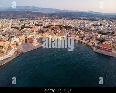 Panorama-Luftaufnahme einer Drohne während der magischen Stunde nach dem Sonnenuntergang des schönen alten venezianischen Hafens von Chania Stadt mit den Lichtern beleuchtet der erstaunliche Leuchtturm, Moschee, venezianischen Werften und alten den Denkmälern und Wahrzeichen in der Nähe des Hafens und des Meeres. Griechenland versucht, seinen Tourismus anzukurbeln und Impfprivilegien gegen die Coronavirus-Pandemie Covid-19, internationale Touristen und Einheimische zu gewähren, da das Land trotz der in Bezug auf die steigende Anzahl von Fällen mit der Covid-19 Coronavirus Delta Mutation Variante stark von der Reise- und Tourismusindustrie abhängig ist. Chania, Cre Stockfoto