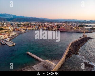 Panorama-Luftaufnahme einer Drohne während der magischen Stunde nach dem Sonnenuntergang des schönen alten venezianischen Hafens von Chania Stadt mit den Lichtern beleuchtet der erstaunliche Leuchtturm, Moschee, venezianischen Werften und alten den Denkmälern und Wahrzeichen in der Nähe des Hafens und des Meeres. Griechenland versucht, seinen Tourismus anzukurbeln und Impfprivilegien gegen die Coronavirus-Pandemie Covid-19, internationale Touristen und Einheimische zu gewähren, da das Land trotz der in Bezug auf die steigende Anzahl von Fällen mit der Covid-19 Coronavirus Delta Mutation Variante stark von der Reise- und Tourismusindustrie abhängig ist. Chania, Cre Stockfoto