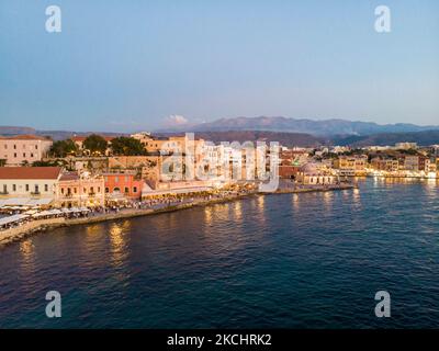 Panorama-Luftaufnahme einer Drohne während der magischen Stunde nach dem Sonnenuntergang des schönen alten venezianischen Hafens von Chania Stadt mit den Lichtern beleuchtet der erstaunliche Leuchtturm, Moschee, venezianischen Werften und alten den Denkmälern und Wahrzeichen in der Nähe des Hafens und des Meeres. Griechenland versucht, seinen Tourismus anzukurbeln und Impfprivilegien gegen die Coronavirus-Pandemie Covid-19, internationale Touristen und Einheimische zu gewähren, da das Land trotz der in Bezug auf die steigende Anzahl von Fällen mit der Covid-19 Coronavirus Delta Mutation Variante stark von der Reise- und Tourismusindustrie abhängig ist. Chania, Cre Stockfoto