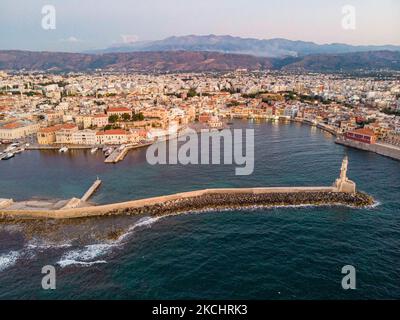 Panorama-Luftaufnahme einer Drohne während der magischen Stunde nach dem Sonnenuntergang des schönen alten venezianischen Hafens von Chania Stadt mit den Lichtern beleuchtet der erstaunliche Leuchtturm, Moschee, venezianischen Werften und alten den Denkmälern und Wahrzeichen in der Nähe des Hafens und des Meeres. Griechenland versucht, seinen Tourismus anzukurbeln und Impfprivilegien gegen die Coronavirus-Pandemie Covid-19, internationale Touristen und Einheimische zu gewähren, da das Land trotz der in Bezug auf die steigende Anzahl von Fällen mit der Covid-19 Coronavirus Delta Mutation Variante stark von der Reise- und Tourismusindustrie abhängig ist. Chania, Cre Stockfoto