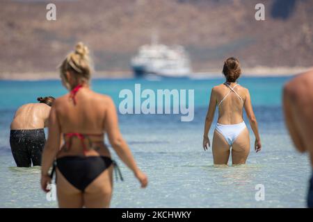 Menschen, Männer und Frauen mit Bikini und Badeanzug genießen das Wasser des Balos Beach oder den Schatten unter einem Schirm der lokalen Strandbar an der unglaublichen Lagune, mit dem Pool wie türkisblaues exotisches und tropisches Wasser des Mittelmeers befindet sich in der Region Chania auf der Insel Kreta. Balos ist einer der meistbesuchten Strände Kretas und beliebt bei Besuchern auf der ganzen Welt. Kristallklares Wasser, die Lagune, felsige steile Berge, eine Strandbar mit Sonnenschirmen und Schatten mit Getränken und eine Pirateninsel befinden sich in derselben Region, die mit einem 20-minütigen Trek oder Boot erreichbar ist. Griechenland ist TRY Stockfoto