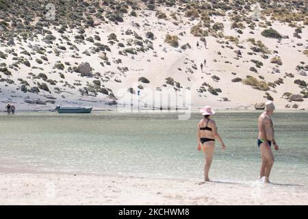 Die Menschen genießen das Wasser und andere die Sanddünen des Balos Beach, die unglaubliche Lagune, mit dem Pool wie türkisblaues exotisches und tropisches Wasser des Mittelmeers befindet sich in der Region Chania auf der Insel Kreta. Balos ist einer der meistbesuchten Strände Kretas und beliebt bei Besuchern auf der ganzen Welt. Kristallklares Wasser, die Lagune, felsige steile Berge, eine Strandbar mit Sonnenschirmen und Schatten mit Getränken und eine Pirateninsel befinden sich in derselben Region, die mit einem 20-minütigen Trek oder Boot erreichbar ist. Griechenland versucht, seinen Tourismus anzukurbeln und gegen Covid geimpft zu werden Stockfoto