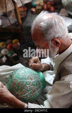 Ein 78-jähriger Handwerker aus Kaschmir malt am 26. Juni 2010 in einer Werkstatt am Dal Lake in Srinagar, Kaschmir, Indien, ein kompliziertes Design auf eine Papiermaché-Vase. (Foto von Creative Touch Imaging Ltd./NurPhoto) Stockfoto