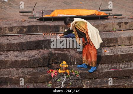 Frau zündet am 10. Dezember 2011 an den Stufen, die zum Ufer des Bagmati-Flusses bei den Pashupatinath-Einäscherungsghats in Kathmandu, Nepal, führen, Weihrauch von einem Körper an, der eingeäschert werden soll. Nach hinduistischer Religion und Tradition müssen die Toten eingeäschert werden. Die Körper werden nach dem Brauch eingeäschert und die Asche und die Überreste werden in die heiligen Wasser gefegt. Die Bagmati verläuft weiter südlich in den Ganges und gilt für Hindus gleichermaßen heilig. Der Komplex in Pashupatinath ist der heiligste Hindu-Ort in Nepal. (Foto von Creative Touch Imaging Ltd./NurPhoto) Stockfoto