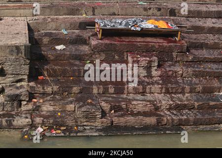 Der Körper auf einer Bahre, die auf die Einäscherung wartet, ruht auf den Stufen, die am 10. Dezember 2011 zum Ufer des Bagmati-Flusses bei den Pashupatinath-Einäscherungsghats in Kathmandu, Nepal, führen. Nach hinduistischer Religion und Tradition müssen die Toten eingeäschert werden. Die Körper werden nach dem Brauch eingeäschert und die Asche und die Überreste werden in die heiligen Wasser gefegt. Die Bagmati verläuft weiter südlich in den Ganges und gilt für Hindus gleichermaßen heilig. Der Komplex in Pashupatinath ist der heiligste Hindu-Ort in Nepal. (Foto von Creative Touch Imaging Ltd./NurPhoto) Stockfoto
