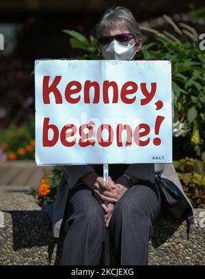 Eine Frau, die eine Gesichtsmaske trug, sah ein Plakat mit der Aufschrift „Kenny, Begone!“. Seit 11. Tagen in Folge protestieren Menschen gegen den Plan der Provinzregierung von Alberta, die obligatorischen COVID-19-Isolationsregeln aufzuheben, die Kontaktverfolgung und die Tests auf dem Gelände der Alberta Legislature zu verfolgen. Am Montag, den 9. August 2021, in Edmonton, Alberta, Kanada. (Foto von Artur Widak/NurPhoto) Stockfoto