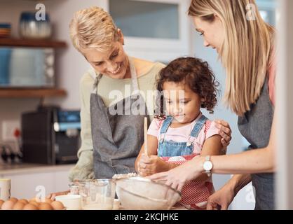 Oma, Mutter und Kind backen in der Küche zusammen, während das Mädchen lernt, Kuchenmischung, Pfannkuchenteig oder Muffin-Mischung zu mischen. Familie Kochen Dessert, Kind Stockfoto