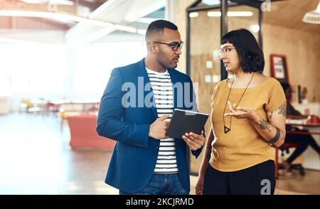 Nur zwei kreative Pioniere arbeiten zusammen. Zwei Designer arbeiten gemeinsam an einem digitalen Tablet in einem Büro. Stockfoto
