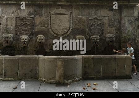 Einige Kinder spielen in der Fuente de los Caños de San Francisco (Aviles), ein einzigartiges Denkmal, das aus einem frontalen besteht, aus dem sechs menschliche Köpfe hervorgehen, die das Wasser in Richtung eines rechteckigen Beckens fließen, das in seiner Mitte eine ovale Form annimmt. AVILES 08-17-2021 (Foto von Joaquin Gomez Sastre/NurPhoto) Stockfoto