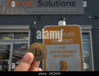 A nitizen hält einen physischen Gedenkbitcoin neben dem Schild „Reserved Parking for Cryptocurrency Enthusiasts“ vor dem Bitcoin Solutions Cryptocurrency Center in Edmonton. Am Dienstag, den 17. August 2021, in Edmonton, Alberta, Kanada. (Foto von Artur Widak/NurPhoto) Stockfoto