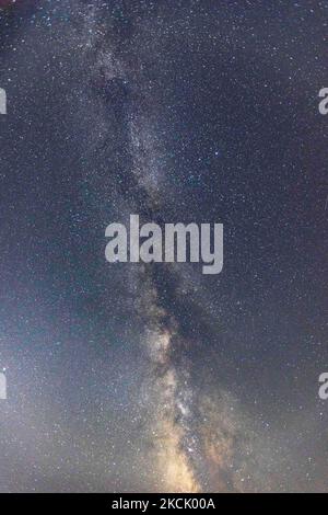 Die Milchstraße im dunklen griechischen Nachthimmel mit den leuchtenden Sternen, Teil der Galaxie, die unser Sonnensystem enthält, wie von einem Sandstrand in Chalkidiki, Griechenland aus gesehen, mit einem sichtbaren Boot und Dörfern auf der anderen Seite, die das Licht auf der Wasseroberfläche reflektieren. Die Langzeitaufnahmen der Milchstraße wurden vom Koviou-Sandstrand, einer typischen mediterranen Landschaft der Ägäis, in der Nähe von Nikiti aufgenommen. Aufgrund der Coronavirus-Pandemie Covid-19 war Griechenland nicht überfüllt mit Touristen und Sicherheitsmassnahmen, die während der Sommerzeit angewendet wurden, was dazu beigetragen hat, dass der Himmel dunkler und dunkler wurde Stockfoto