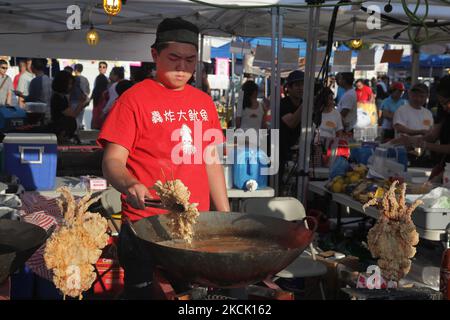 Der Lebensmittelhändler fritiert am 24. Juli 2015 auf einem chinesischen Markt in Markham (Ontario, Kanada) „quid Lutscher“ (große gebratene Tintenfische, die mit einem Teig auf einem Stock bedeckt sind) in einem großen Wok, der mit kochendem Öl gefüllt ist. (Foto von Creative Touch Imaging Ltd./NurPhoto) Stockfoto