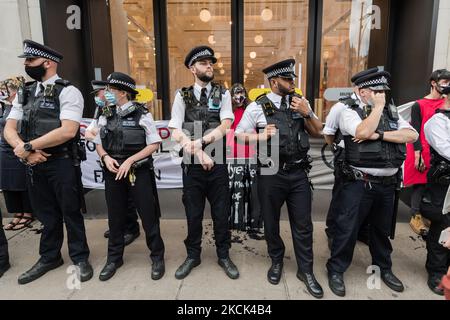 LONDON, GROSSBRITANNIEN – 24. AUGUST 2021: Umweltaktivisten des Extinction Rebellion sind von Polizeibeamten umgeben, als sie am 24. August 2021 in London, England, vor dem Kaufhaus Selfridges in der Oxford Street gegen das Vertrauen der Modeindustrie auf synthetische Polyester- und Nylontextilien aus Erdöl protestieren. (Foto von Wiktor Szymanowicz/NurPhoto) Stockfoto