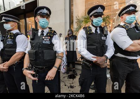 LONDON, GROSSBRITANNIEN – 24. AUGUST 2021: Umweltaktivisten des Extinction Rebellion sind von Polizeibeamten umgeben, als sie am 24. August 2021 in London, England, vor dem Kaufhaus Selfridges in der Oxford Street gegen das Vertrauen der Modeindustrie auf synthetische Polyester- und Nylontextilien aus Erdöl protestieren. (Foto von Wiktor Szymanowicz/NurPhoto) Stockfoto