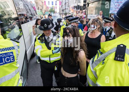 LONDON, GROSSBRITANNIEN – 24. AUGUST 2021: Umweltaktivisten von Extinction Rebellion werden verhaftet und von Polizeibeamten nach einem Protest vor dem Kaufhaus Selfridges in der Oxford Street gegen das Vertrauen der Modeindustrie auf synthetische Polyester- und Nylontextilien aus Erdöl am 24. August 2021 in London, England, aufgrund der Klimakrise und der ökologischen Notlage weggeführt. (Foto von Wiktor Szymanowicz/NurPhoto) Stockfoto