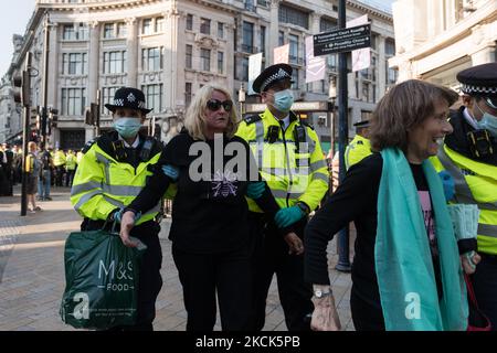 LONDON, GROSSBRITANNIEN - 25. AUGUST 2021: Polizisten führen zwei hochrangige Demonstranten vom Extinction Rebellion weg, die am dritten Tag der „Impossible Rebellion“ verhaftet wurden, weil sie den Oxford Circus blockiert hatten. Eine neue Welle von Protesten und zivilen Ungehorsamsmaßnahmen, die mindestens zwei Wochen andauern soll, um einen sofortigen Stopp aller neuen Investitionen in fossile Brennstoffe durch die britische Regierung und Finanzkonzerne zu fordern, inmitten der Klimakrise und der ökologischen Notlage am 25. August 2021 in London, England. (Foto von Wiktor Szymanowicz/NurPhoto) Stockfoto