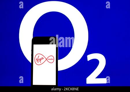 In dieser Abbildung ist ein Virgin Media Inc-Logo auf einem Smartphone mit einem O2-Logo im Hintergrund zu sehen. (Foto von DAX Images/NurPhoto) Stockfoto