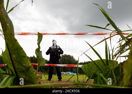 Soldaten der polnischen Armee umkreisen eine Gruppe von Einwanderern aus Afghanistan an der weißrussischen Grenze und verhindern ihre Einreise in das Land in Usnarz Gorny, Polen, am 27. August 2021. Die Armee und die Polizei hielten die Migranten an der Grenze an und verhinderten, dass sie nach Polen einmarschieren konnten, die Armee verweigerte auch den Zugang zu Asylverfahren, medizinischer Hilfe und Lebensmitteln. Journalisten und Wohltätigkeitsarbeiter werden etwa 300 Meter entfernt gehalten. Die Aktionen der polnischen Regierung wurden weithin kritisiert. Die polnische Regierung beschloss außerdem, einen Zaun zu errichten, um dem Zustrom von Migranten, die über Belarus wandern, ein Ende zu setzen b Stockfoto