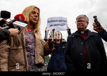 Aktivisten protestieren, während Soldaten der polnischen Armee eine Gruppe von Einwanderern aus Afghanistan an der weißrussischen Grenze umkreisen und ihre Einreise in das Land in Usnarz Gorny, Polen, am 27. August 2021 verhindern. Die Armee und die Polizei hielten die Migranten an der Grenze an und verhinderten, dass sie nach Polen einmarschieren konnten, die Armee verweigerte auch den Zugang zu Asylverfahren, medizinischer Hilfe und Lebensmitteln. Journalisten und Wohltätigkeitsarbeiter werden etwa 300 Meter entfernt gehalten. Die Aktionen der polnischen Regierung wurden weithin kritisiert. Die polnische Regierung beschloss auch, einen Zaun zu bauen, um dem Zustrom von Wanderern ein Ende zu setzen Stockfoto