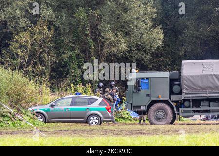 Soldaten der polnischen Armee umkreisen eine Gruppe von Einwanderern aus Afghanistan an der weißrussischen Grenze und verhindern ihre Einreise in das Land in Usnarz Gorny, Polen, am 27. August 2021. Die Armee und die Polizei hielten die Migranten an der Grenze an und verhinderten, dass sie nach Polen einmarschieren konnten, die Armee verweigerte auch den Zugang zu Asylverfahren, medizinischer Hilfe und Lebensmitteln. Journalisten und Wohltätigkeitsarbeiter werden etwa 300 Meter entfernt gehalten. Die Aktionen der polnischen Regierung wurden weithin kritisiert. Die polnische Regierung beschloss außerdem, einen Zaun zu errichten, um dem Zustrom von Migranten, die über Belarus wandern, ein Ende zu setzen b Stockfoto